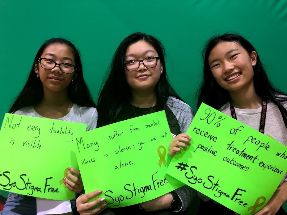 Three students holding messages about mental wellness
